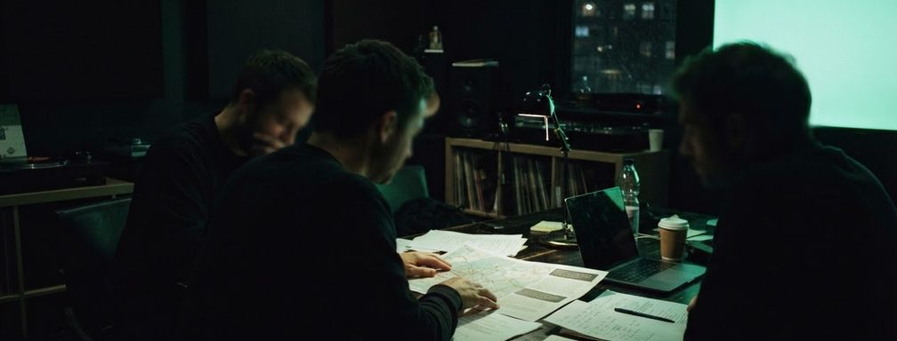 A marketing, legal and procurement team reviewing campaign paperwork together around a desk at night.