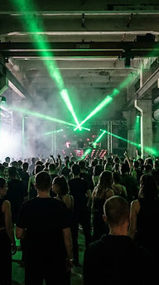 Artist mid guitar solo under green stage beams