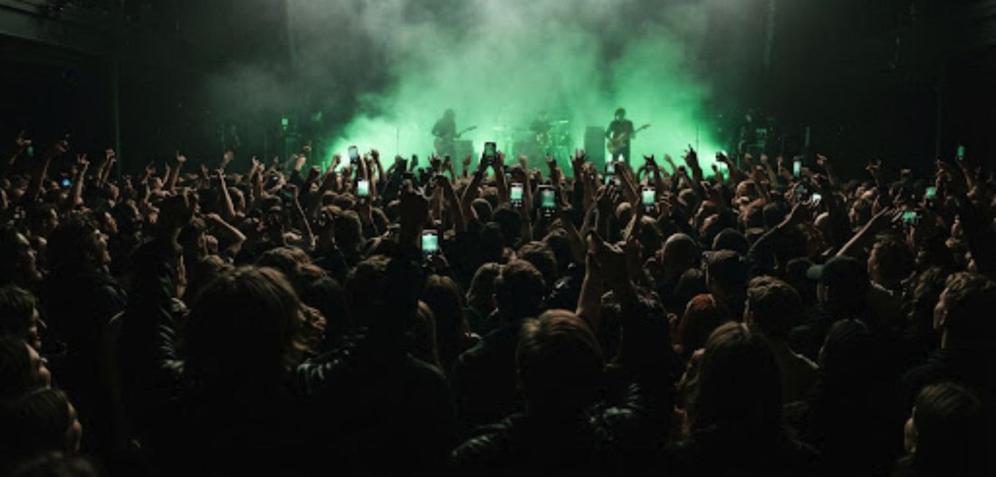 Rear camera: the room with phones and hands up, lit from the stage