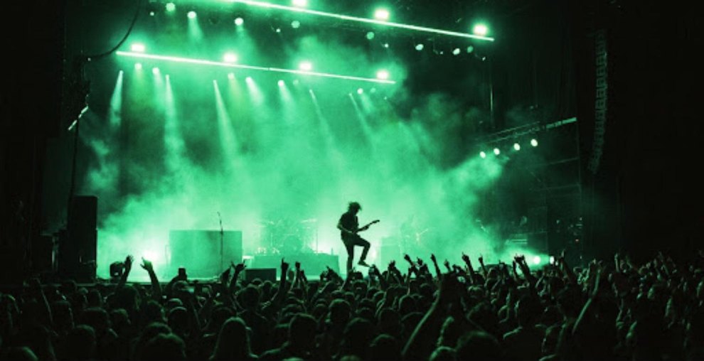 Master feed: the artist on stage under green wash, crowd in silhouette